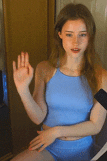 a woman in a blue top and shorts is waving