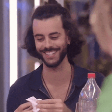 a man with a beard is smiling while holding a napkin and a water bottle