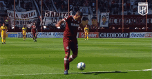 a man kicking a soccer ball on a field with ads for credicoop and experta express