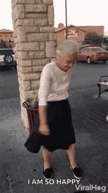 an elderly woman is dancing in front of a brick wall and says i am so happy viralhog