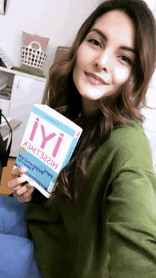 a woman holding a book titled iyi