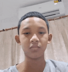 a young boy is taking a selfie in front of a wall air conditioner .