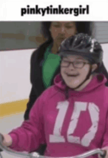 a girl with down syndrome wearing a helmet and a pink sweatshirt with the number 10 on it