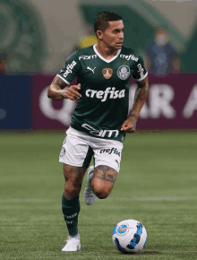 a soccer player wearing a green crefisa jersey runs with the ball