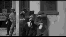 a group of men are standing in front of a building with a sign that says sandwiches and drinks .