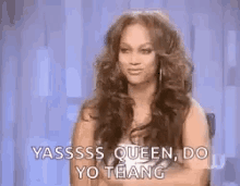 a woman with long hair is sitting in a chair with her arms crossed and saying yassss queen do yo thang .