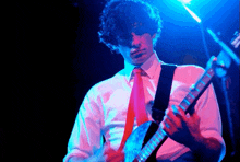 a man in a white shirt and tie is playing a guitar