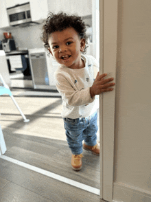 a little boy with curly hair is standing in a doorway