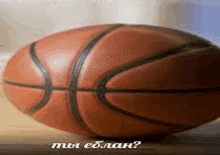 a basketball is sitting on a wooden table next to a sign that says " мы еблан " .