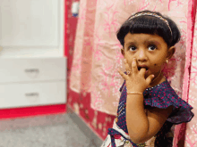 a little girl with a ring on her finger covering her mouth