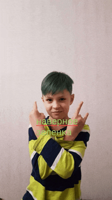 a young boy with green hair is making a peace sign with his fingers