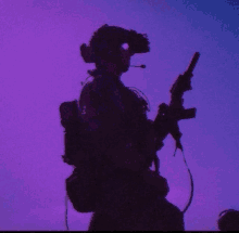 a silhouette of a person holding a gun with a purple sky in the background