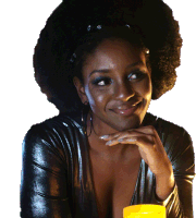 a woman in a black dress is smiling while holding a yellow glass