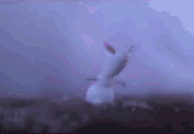 a snowman is flying through the air in a field with a purple sky in the background .