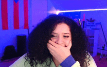 a woman with curly hair covering her mouth with her hand