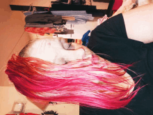 a woman with pink hair is laying on her back with her eyes closed