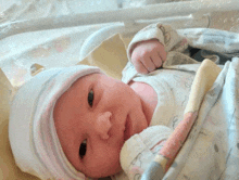 a newborn baby wearing a white hat and blanket