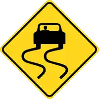 a yellow sign warns of a slippery road with a car on it