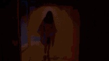 a woman in a bathing suit is walking through a dark tunnel .