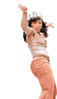 a woman in a tan tank top and orange pants dancing