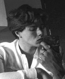 a black and white photo of a man smoking a cigarette and holding a cat .