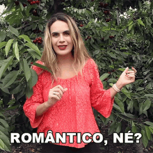 a woman in a red top is standing in front of a cherry tree and says romantico