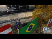 a man in a spiderman suit is sitting on top of a brazilian flag .