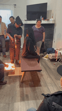 a group of people are gathered in a living room including a woman sitting on a bench