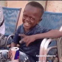 a young boy is sitting in a chair with a can of red bull in his hand .