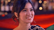 a close up of a woman 's face smiling on a red carpet .