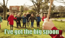 a group of children are playing in a park with a person holding a big spoon in front of them .