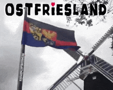 a black and white photo of a windmill and a flag with ostfriesland written on it