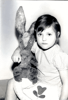 a little girl is holding a stuffed animal rabbit