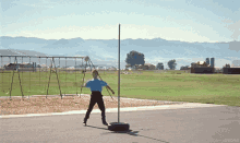 a person is throwing a ball in a field with mountains in the background and a sign that says zuorm