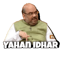 a man with glasses and a beard is pointing at something with the words yahan idhar written below him .