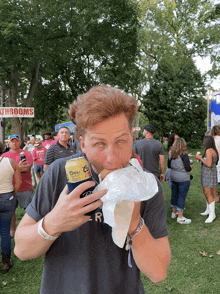 a man eating a sandwich while holding a can of corona