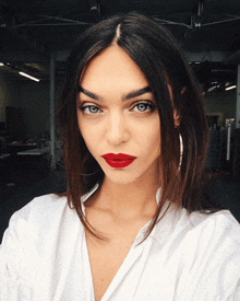 a woman wearing red lipstick and hoop earrings is taking a selfie