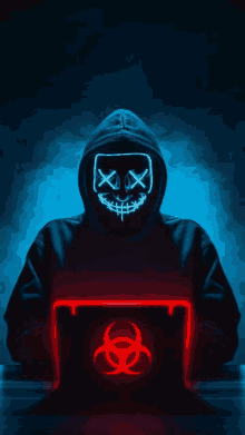 a person wearing a neon mask is sitting in front of a laptop .