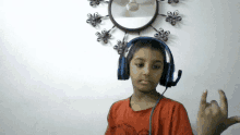 a young boy wearing headphones and a red shirt is making a horn sign