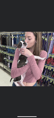 a woman in a pink shirt holds a small brown and white dog