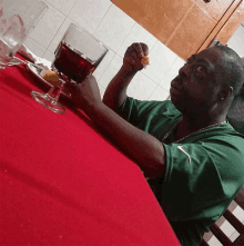 a man sits at a table with a glass of wine and a piece of food