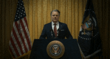 a man in a suit and tie stands at a podium with the seal of the president of the united states on it