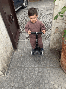 a little boy riding a micro scooter on a tiled floor