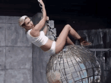 a woman in white underwear is sitting on top of a globe .