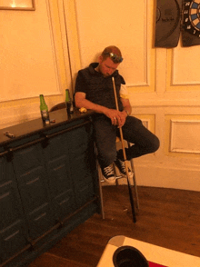 a man sitting in a chair with a pool cue in his hand