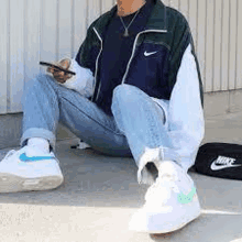 a man is sitting on the ground wearing a nike jacket .