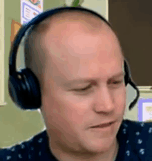 a bald man wearing headphones with a microphone on his head .