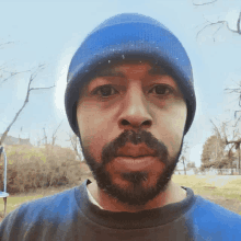 a man with a beard wearing a blue beanie and a blue shirt