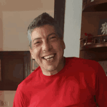 a man wearing a red shirt is smiling with his teeth showing