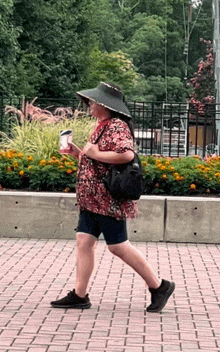 a woman wearing a floral shirt and black shorts is walking down a sidewalk